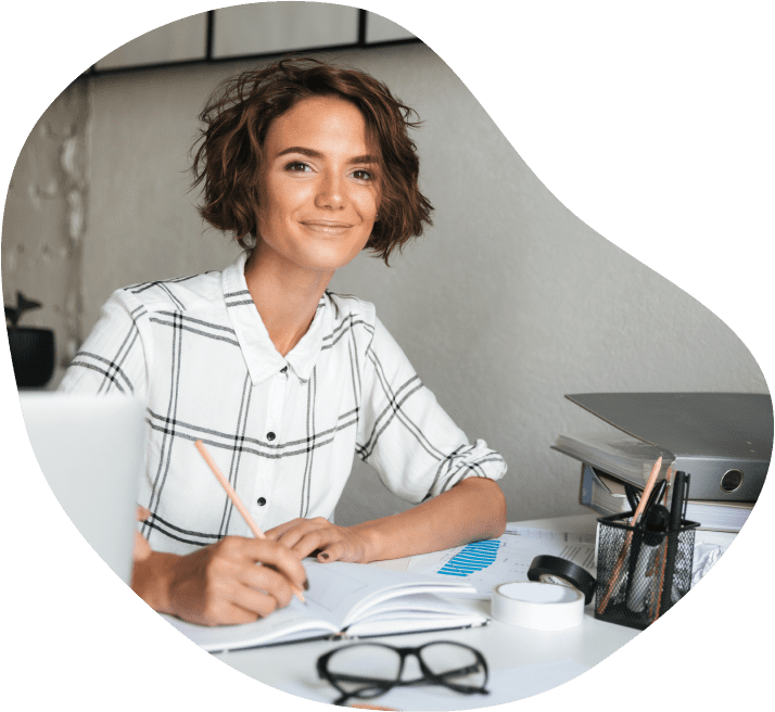 Photo d'une femme installée à son bureau avec un cahier et un stylo